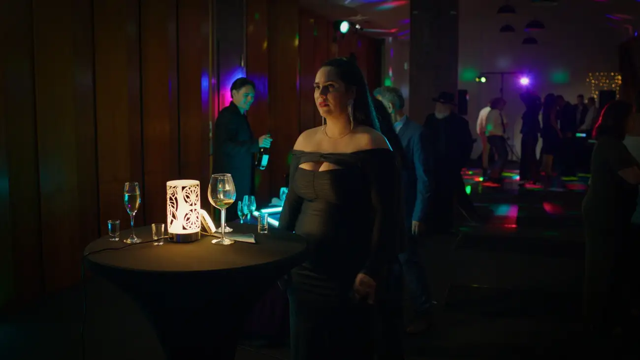 Mariana stands alone at a colourful party.