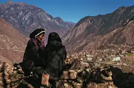 Grandma Xiage-achong chats with producer Liyuan on a cliff overlooking Zhonglu Village.