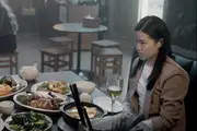 Winson and Elle's look at each other unhappily across a table full of food in a Chinese diner.