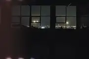 A view of Dunedin at night through dark floor-to-ceiling windows.