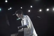 A uniformed high school student playing a piano that is collapsing into the ground.